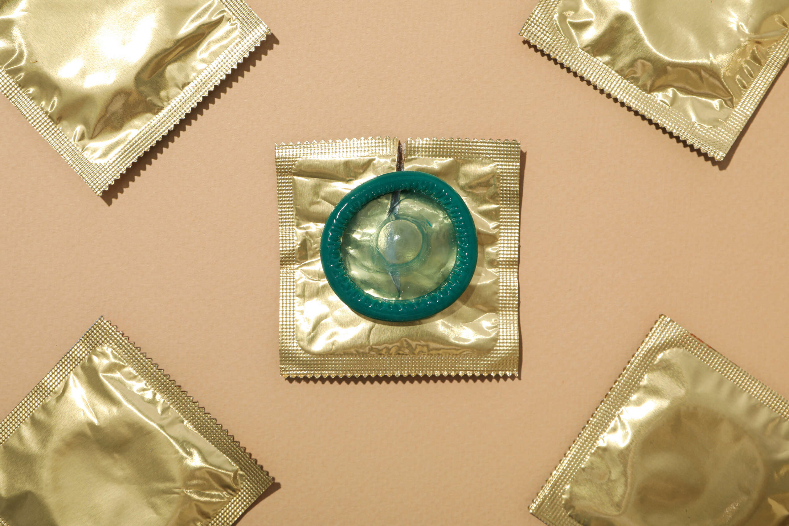 Condoms in a golden wrapper on a light background close-up